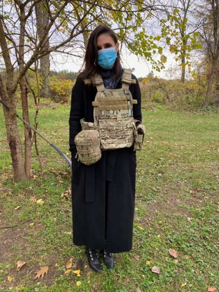 A woman wearing a mask and wearing military garb outside